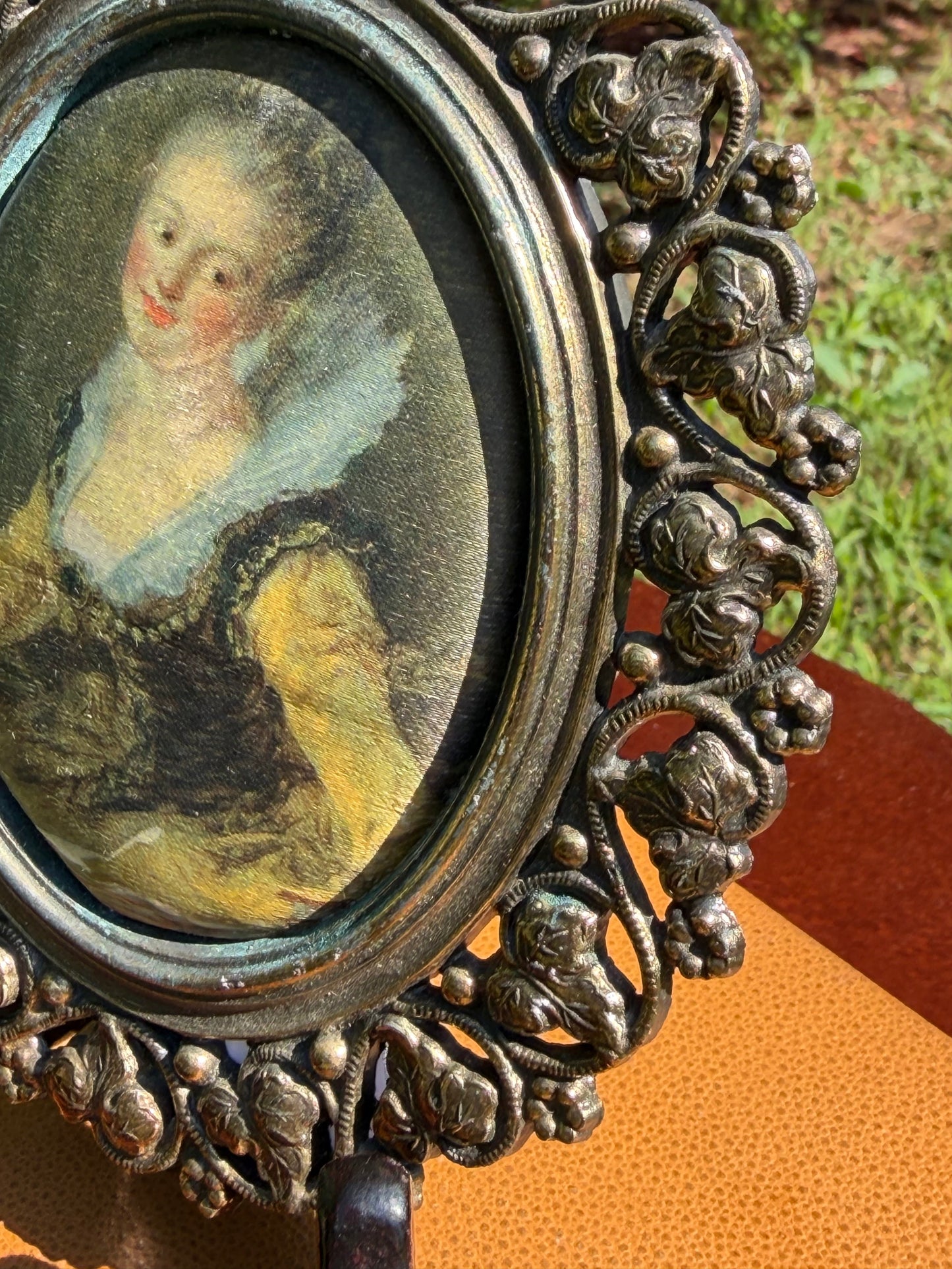 Miniature portrait displayed on easel with vintage books and greenery