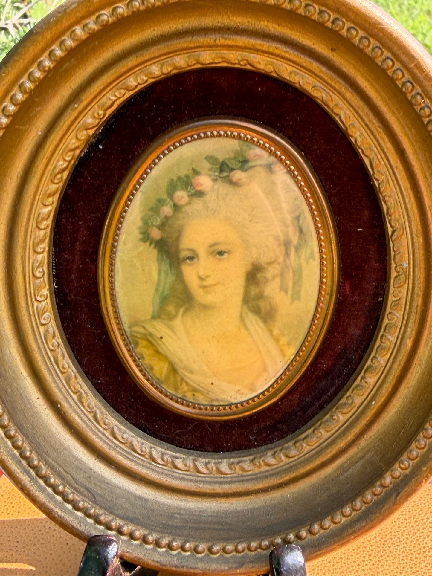 Pair of Cameo Creation miniature portraits in round gilt frames displayed on vintage books