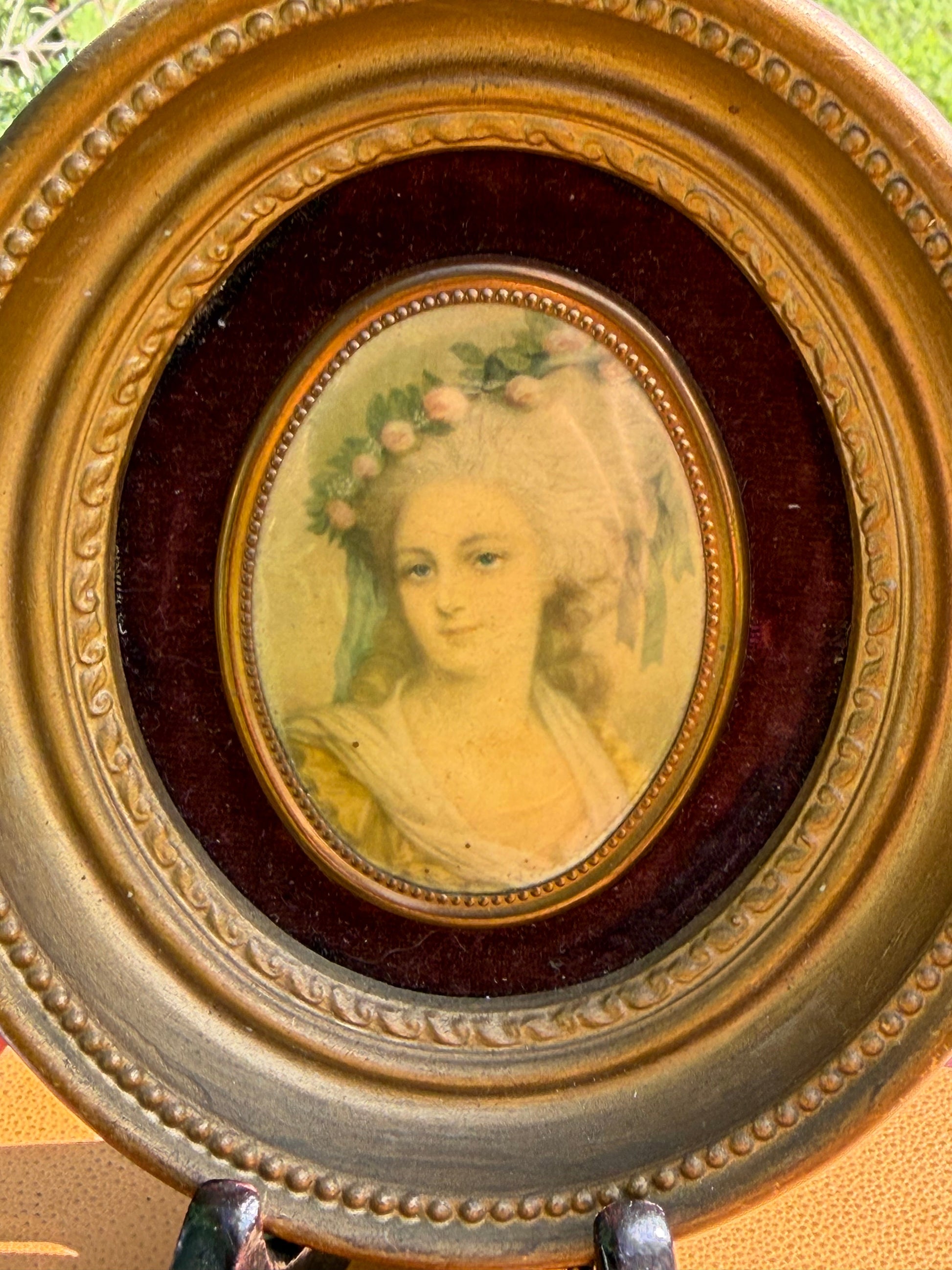 Pair of Cameo Creation miniature portraits in round gilt frames displayed on vintage books