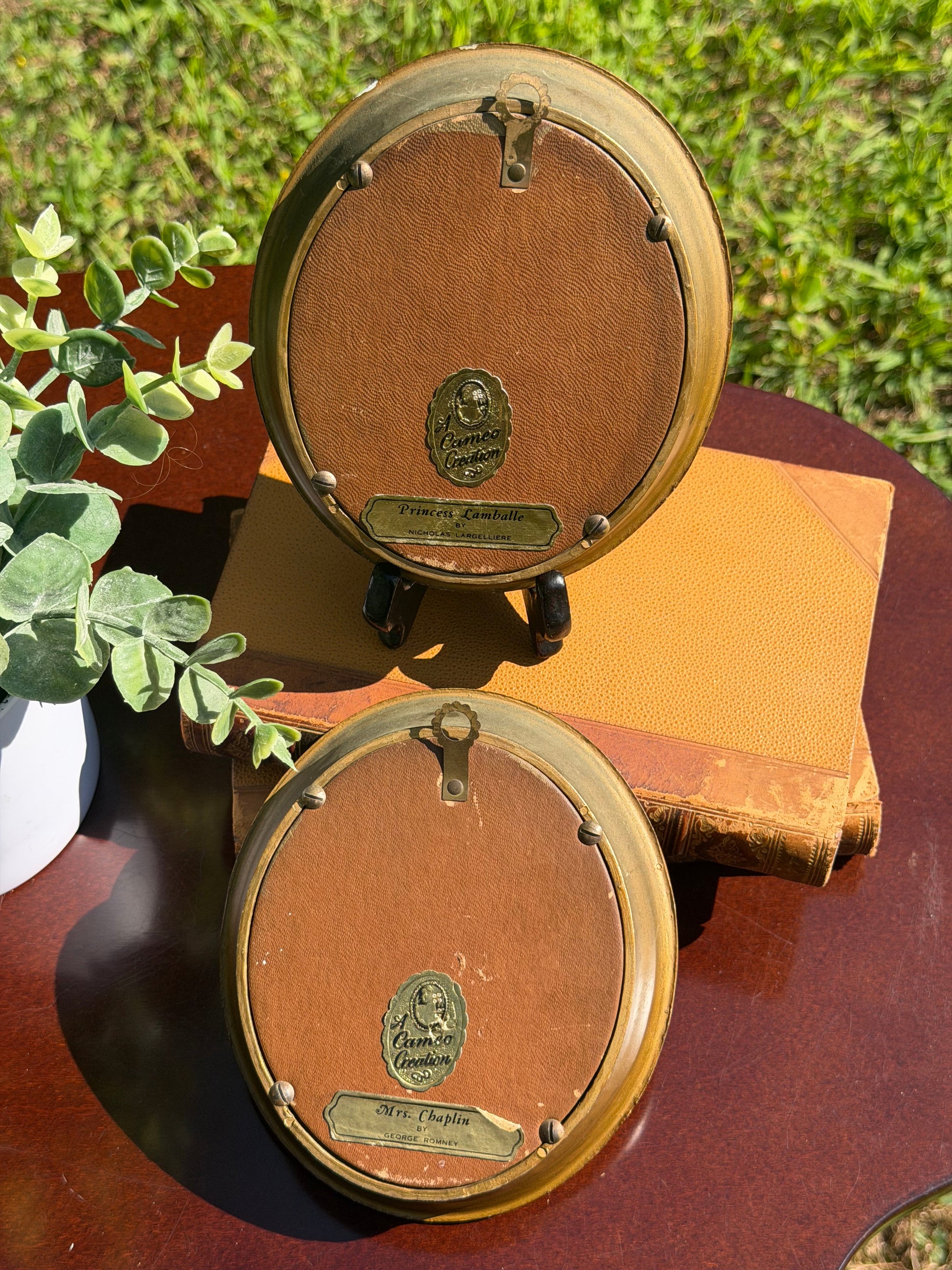 Both miniature portrait frames displayed at angle on vintage books with greenery