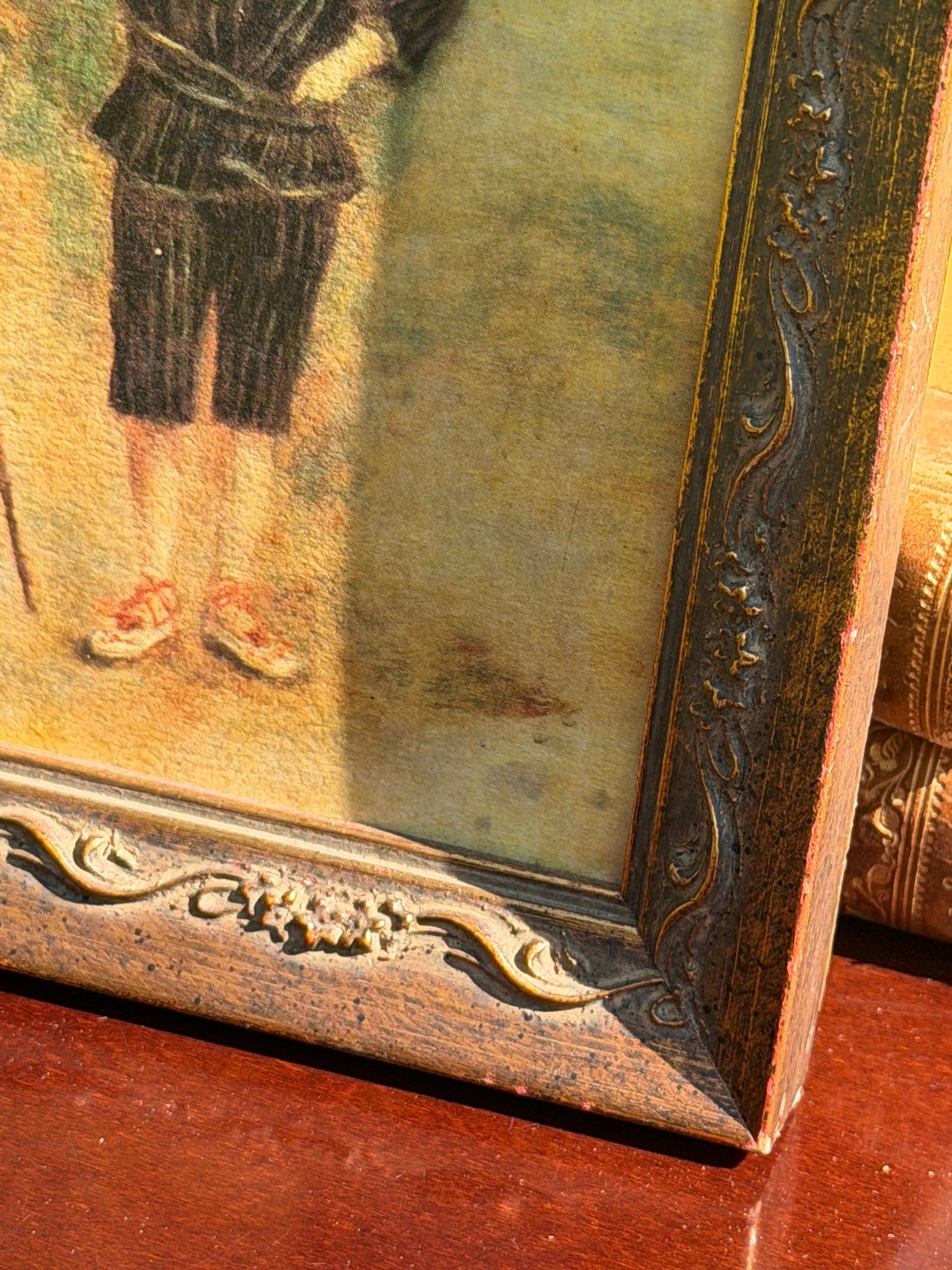 Side angle view of Renoir Fisher Boy print in ornate frame on vintage books